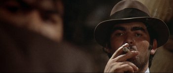 Movie still from “Duck, You Sucker!” (1971), directed by Sergio Leone – A man wearing a hat is smoking a cigarette; Extreme Close Up shot, Over the shoulder angle
