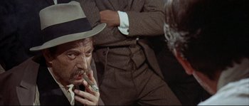 Movie still from “Duck, You Sucker!” (1971), directed by Sergio Leone – An older man smoking a cigarette in front of another older man; Close Up shot, Over the shoulder angle