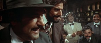 Movie still from “Duck, You Sucker!” (1971), directed by Sergio Leone – A group of men in suits and hats smiling for the camera; Medium shot, Over the shoulder angle
