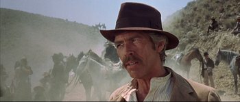 Movie still from “Duck, You Sucker!” (1971), directed by Sergio Leone – A person wearing a hat with horses in the background; Close Up shot, Low angle