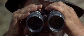 Movie still from “Duck, You Sucker!” (1971), directed by Sergio Leone – A person holding a pair of binoculars in their hands; Extreme Close Up shot, Low angle