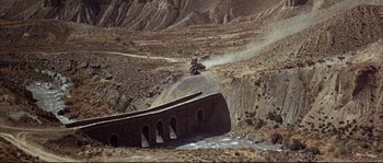 Movie still from “Duck, You Sucker!” (1971), directed by Sergio Leone – A truck driving over a bridge in the desert; Extreme Wide shot, High angle