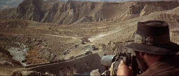 Movie still from “Duck, You Sucker!” (1971), directed by Sergio Leone – A man looking through a telescope at a military vehicle; Wide shot, High angle