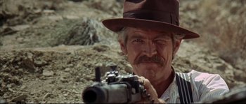 Movie still from “Duck, You Sucker!” (1971), directed by Sergio Leone – An older man with a hat and a gun in his hands; Close Up shot, Over the shoulder angle