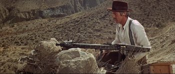 Movie still from “Duck, You Sucker!” (1971), directed by Sergio Leone – A man sitting on a rock holding a machine gun; Medium shot, Low angle