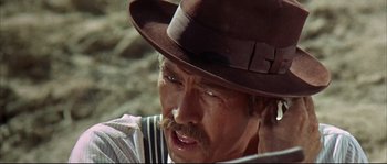 Movie still from “Duck, You Sucker!” (1971), directed by Sergio Leone – A man in a brown hat and a striped shirt; Close Up shot, Over the shoulder angle