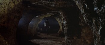 Movie still from “Duck, You Sucker!” (1971), directed by Sergio Leone – A man standing inside of a cave at night; Wide shot, High angle