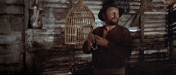 Movie still from “Duck, You Sucker!” (1971), directed by Sergio Leone – A man in a hat holding a bird cage; Medium shot, Low angle