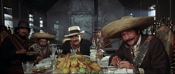 Movie still from “Duck, You Sucker!” (1971), directed by Sergio Leone – A group of men sitting at a table with a lot of fruit; Medium shot, Low angle