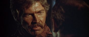 Movie still from “Duck, You Sucker!” (1971), directed by Sergio Leone – A person with a beard wearing a scarf; Close Up shot, Over the shoulder angle