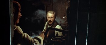 Movie still from “Duck, You Sucker!” (1971), directed by Sergio Leone – An older man holding a sword in a dark room; Medium shot, Over the shoulder angle