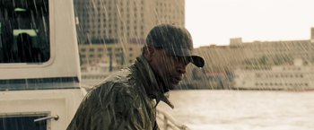 Movie still from “Deja Vu” (2006), directed by Tony Scott – A man wearing a baseball cap standing in the pouring rain; Medium shot, Low angle