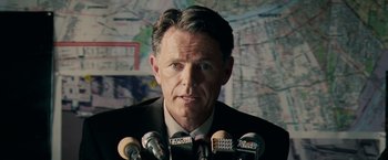 Movie still from “Deja Vu” (2006), directed by Tony Scott – A person with microphones in front of a map; Close Up shot, Over the shoulder angle