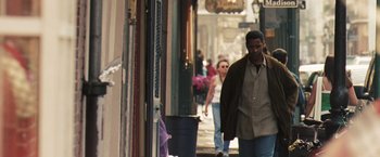 Movie still from “Deja Vu” (2006), directed by Tony Scott – A man walking down a street past a building; Medium shot, Over the shoulder angle