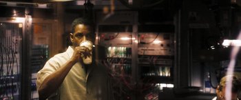 Movie still from “Deja Vu” (2006), directed by Tony Scott – A man drinking a cup of coffee in a dark room; Medium shot, High angle