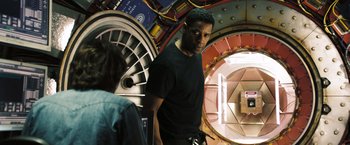 Movie still from “Deja Vu” (2006), directed by Tony Scott – A man standing next to a woman inside a building; Medium shot, Over the shoulder angle