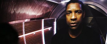 Movie still from “Deja Vu” (2006), directed by Tony Scott – A man in black shirt in front of a metal wall; Close Up shot, Low angle