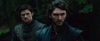 Movie still from “Dracula Untold” (2014), directed by Gary Shore – A man with long black hair standing next to another man; Close Up shot, Over the shoulder angle