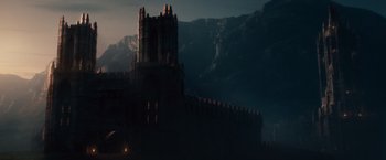 A castle in the middle of the night with mountains in the background