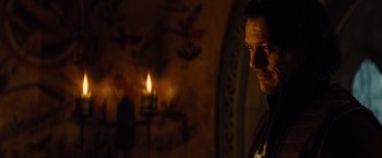 Movie still from “Dracula Untold” (2014), directed by Gary Shore – A man standing in front of a lit candle in a room; Close Up shot, Over the shoulder angle