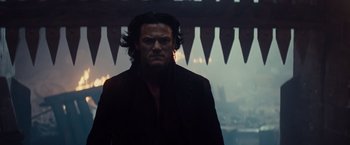 Movie still from “Dracula Untold” (2014), directed by Gary Shore – A man with long black hair wearing a black coat; Close Up shot, Low angle