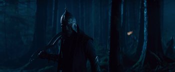 Movie still from “Dracula Untold” (2014), directed by Gary Shore – A man in a helmet is standing in the woods; Medium shot, Low angle