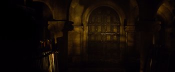 Movie still from “Dracula Untold” (2014), directed by Gary Shore – A dark room with a large wooden door; Wide shot, High angle