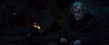Movie still from “Dracula Untold” (2014), directed by Gary Shore – A man sitting in front of a fire pit; Medium shot, Over the shoulder angle
