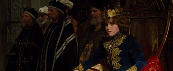 Movie still from “Dracula Untold” (2014), directed by Gary Shore – A young boy wearing a gold crown sitting next to two older men; Medium shot, High angle