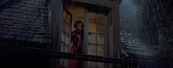 Movie still from “Désirée” (1954), directed by Henry Koster – A woman in a red dress standing in front of an open window; Medium shot, Low angle
