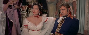 Movie still from “Désirée” (1954), directed by Henry Koster – A woman in a white dress standing next to a man in a suit; Medium shot, High angle