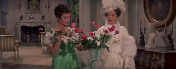 Movie still from “Désirée” (1954), directed by Henry Koster – Two women standing next to each other holding a vase of roses; Medium shot, Over the shoulder angle
