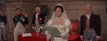 Movie still from “Désirée” (1954), directed by Henry Koster – A woman in a wedding dress reading a paper; Medium shot, Over the shoulder angle