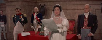 Movie still from “Désirée” (1954), directed by Henry Koster – A woman in a wedding dress holding a sheet of paper in front of a man; Medium shot, Over the shoulder angle