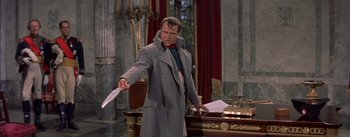 Movie still from “Désirée” (1954), directed by Henry Koster – A man in a long grey coat holding a knife; Medium shot, Over the shoulder angle