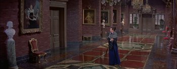 Movie still from “Désirée” (1954), directed by Henry Koster – A woman holding a cane in a room with paintings on the walls; Wide shot, High angle