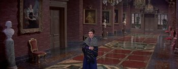 Movie still from “Désirée” (1954), directed by Henry Koster – A woman standing in front of a wall in a room; Wide shot, High angle