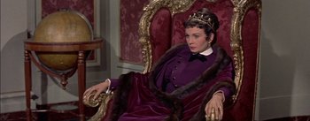 Movie still from “Désirée” (1954), directed by Henry Koster – A woman sitting in a chair wearing a purple dress and a crown; Medium shot, High angle