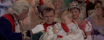 Movie still from “Désirée” (1954), directed by Henry Koster – A man holding a baby while holding a wine glass; Medium shot, Over the shoulder angle