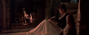Movie still from “Désirée” (1954), directed by Henry Koster – A woman sitting in front of a fireplace reading a book; Medium shot, High angle