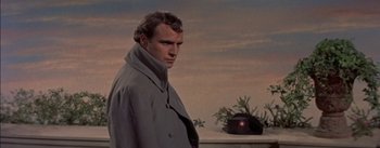Movie still from “Désirée” (1954), directed by Henry Koster – A man wearing a gray coat standing next to a potted plant; Close Up shot, Low angle