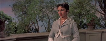 Movie still from “Désirée” (1954), directed by Henry Koster – A woman standing in front of trees and a building; Close Up shot, Low angle