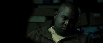 Movie still from “Eagle Eye” (2008), directed by D.J. Caruso – A man with a bald head is sitting in a dark room; Close Up shot, Over the shoulder angle