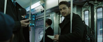 Movie still from “Eagle Eye” (2008), directed by D.J. Caruso – A man with a notebook on a public transit bus; Medium shot, Over the shoulder angle