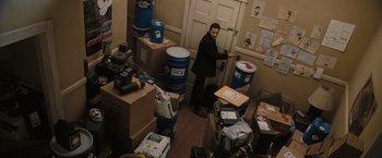 Movie still from “Eagle Eye” (2008), directed by D.J. Caruso – A man standing in front of a room filled with boxes; Wide shot, High angle