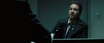 Movie still from “Eagle Eye” (2008), directed by D.J. Caruso – A man wearing a suit and tie sitting in front of a mirror; Close Up shot, Over the shoulder angle