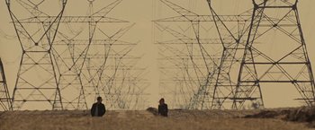 Movie still from “Eagle Eye” (2008), directed by D.J. Caruso – Two people are standing in a field near some power lines; Extreme Wide shot, Low angle