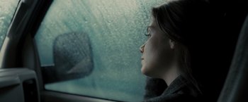 Movie still from “Eagle Eye” (2008), directed by D.J. Caruso – A woman sitting in the passenger seat of a car looking out the window; Close Up shot, Over the shoulder angle