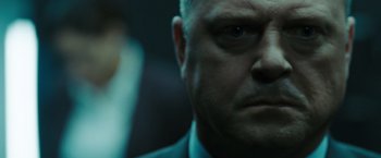Movie still from “Eagle Eye” (2008), directed by D.J. Caruso – A man in a suit looking into the camera; Close Up shot, Over the shoulder angle