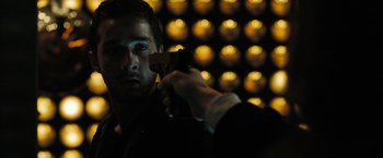 Movie still from “Eagle Eye” (2008), directed by D.J. Caruso – A man holding a gun pointed at a camera; Close Up shot, Over the shoulder angle